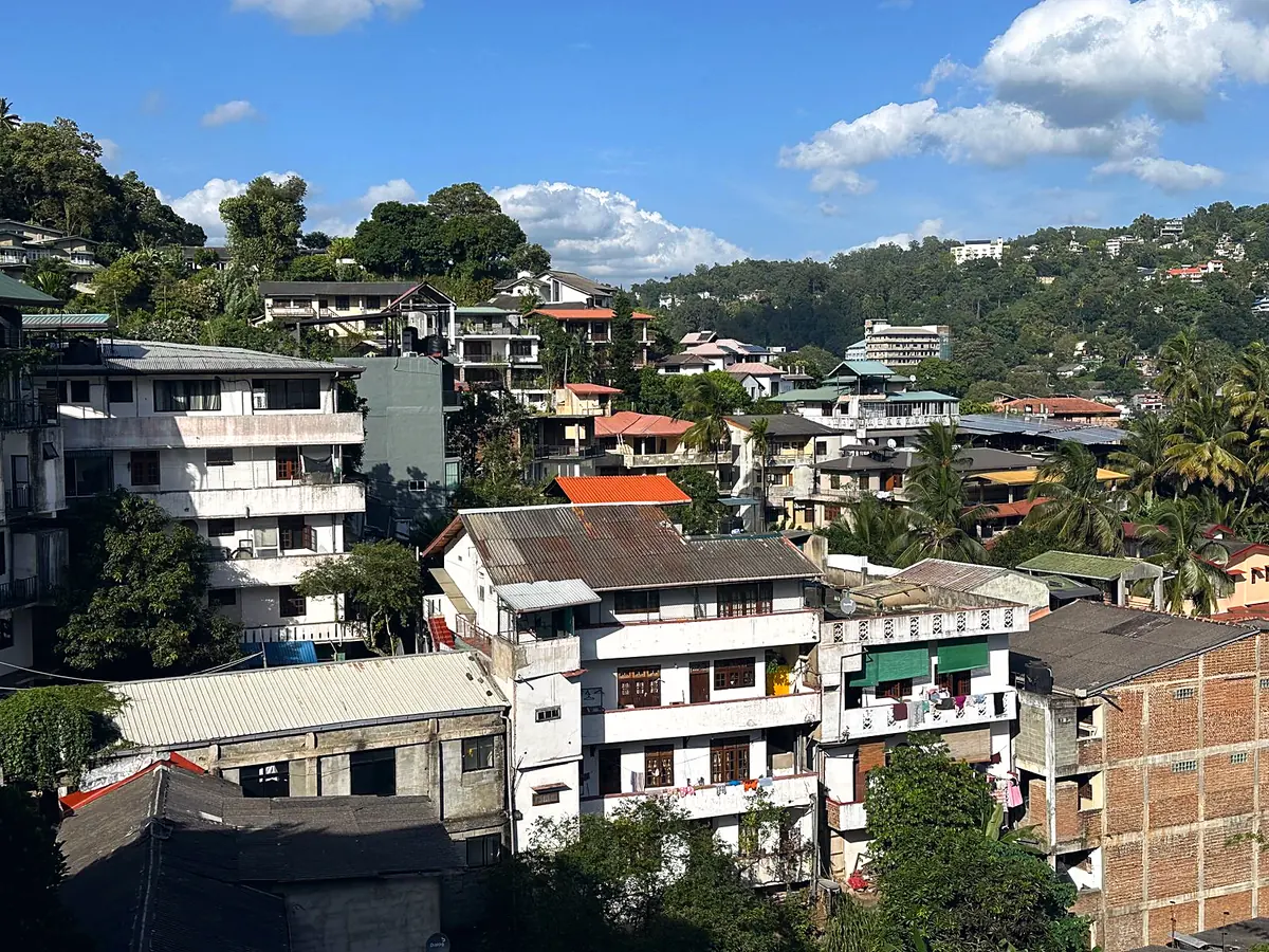 Homes on a hillside in Kandy, Sri Lanka, under a blue sky